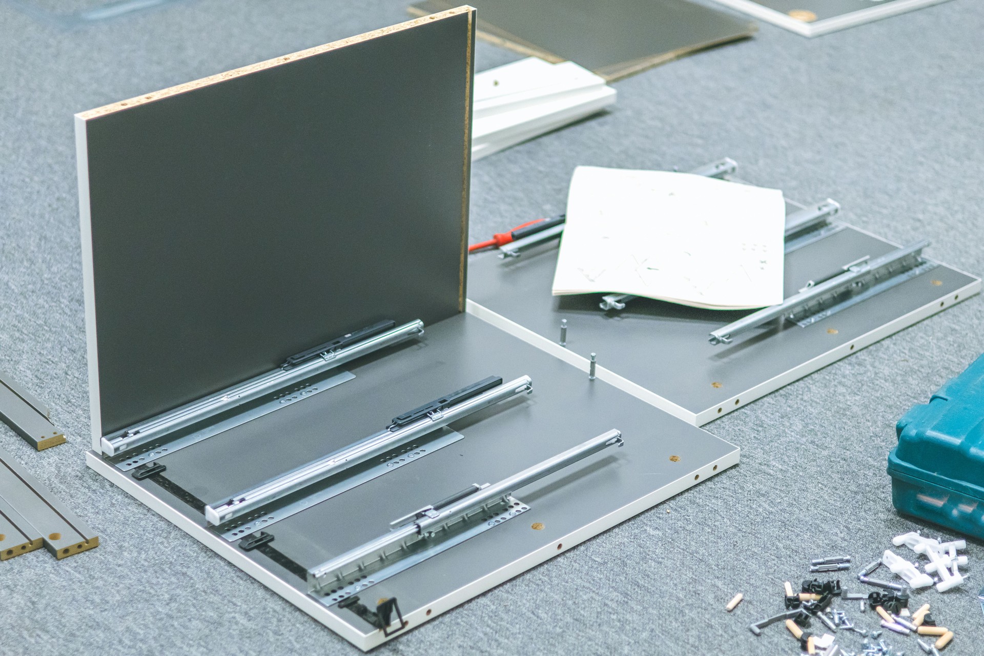 Close up of parts of furniture, screws, nuts, bolts, and tools on the floor inside modern office workspace ready for assembly.
